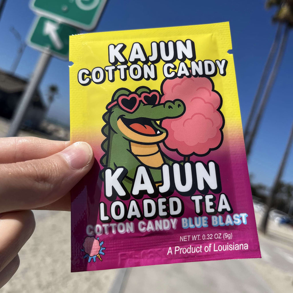 Kajun Cotton Candy Loaded Tea packet held by a hand with a blue sky background